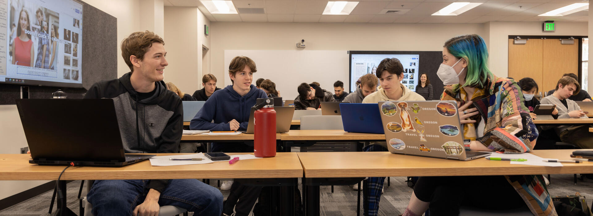 Students sit in an OSU classroom talking as a small group.